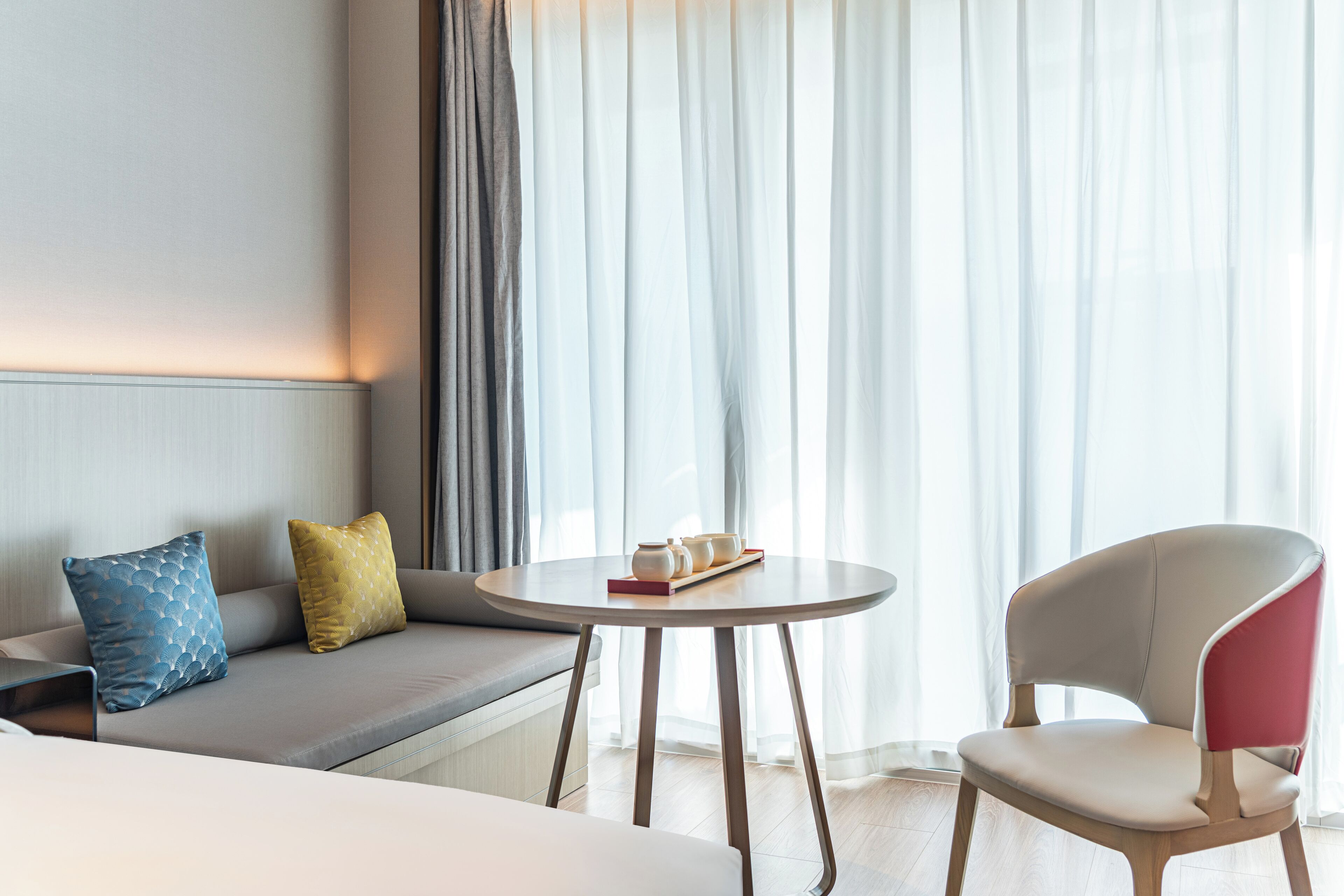 Een moderne hotelkamer met een bank, een rond tafel en een stoel.