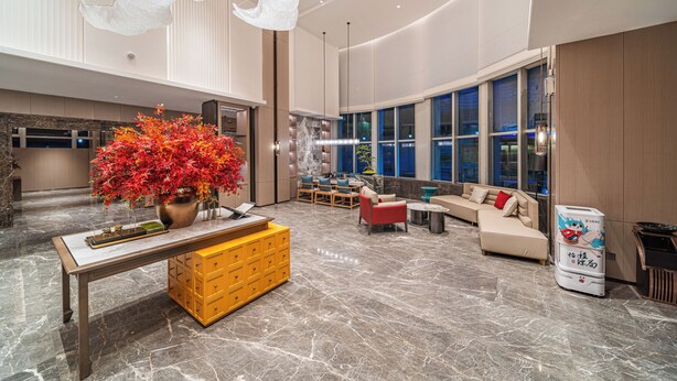 A spacious lobby with a marble floor, a central table with drawers, a sofa set, and a large window offering a view of the city. - Echeng Hotel Guangzhou Baiyun Station (Guangzhou)