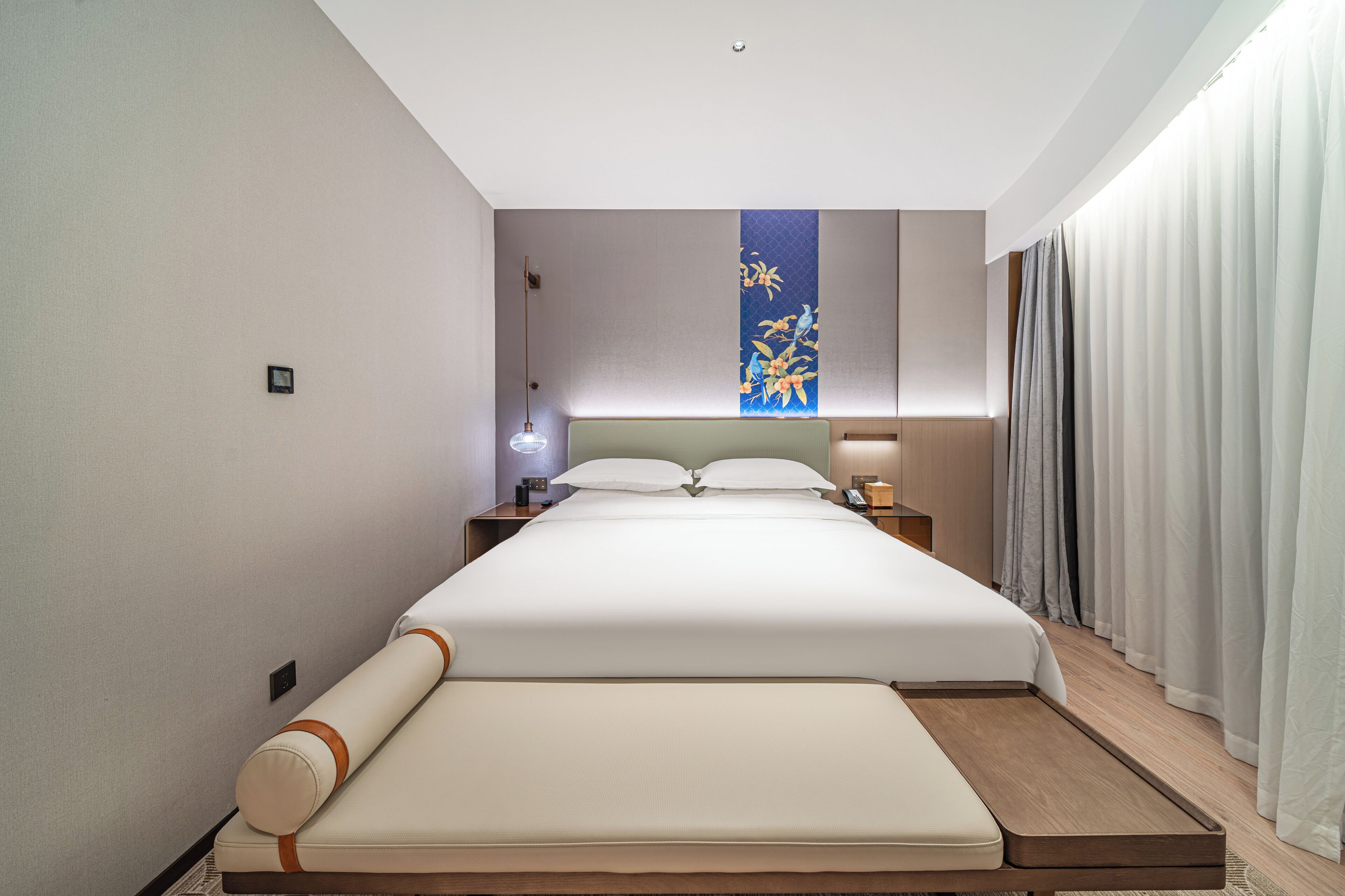 Een moderne hotelkamer met een groot bed, een nachtkastje en een wandlamp.