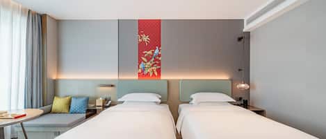Een hotelkamer met twee bedden, een zithoekje, een bureau en een decoratief wandpaneel.