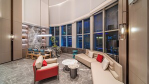 A spacious living area with a curved ceiling, a sofa set, a coffee table, and a dining area with chairs and a table. - Echeng Hotel Guangzhou Baiyun Station (Guangzhou)