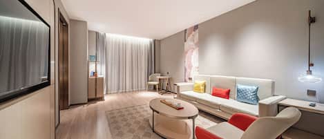 A modern living room with a sofa, a red chair, a coffee table, and a large window with curtains.