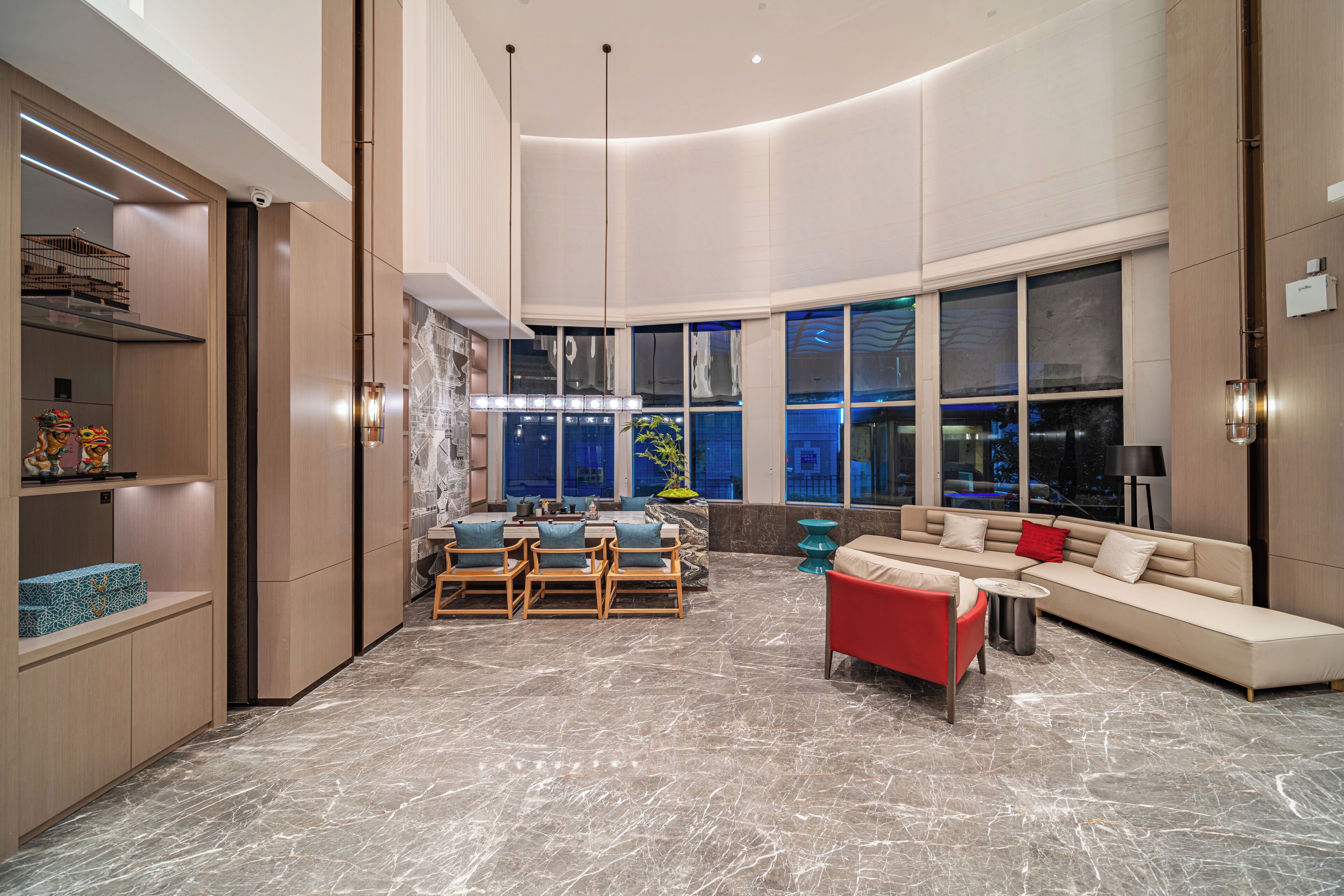 A spacious living area with a marble floor, a sofa, a red armchair, and a dining set.