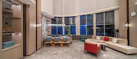 A spacious living area with a marble floor, a sofa, a red armchair, and a dining set.