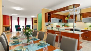 A modern kitchen with a central island, built-in appliances, and a dining area with a large table set for six. - Garden & Terrace Villa by Interhome (Karlin Liben)