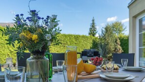 A dining table set with plates, glasses, a pitcher of orange juice, and a vase with flowers. - Garden & Terrace Villa by Interhome (Karlin Liben)