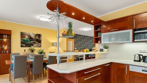 A modern kitchen with wooden cabinets, a built-in microwave, and a dining area with chairs and a table. - Garden & Terrace Villa by Interhome (Karlin Liben)
