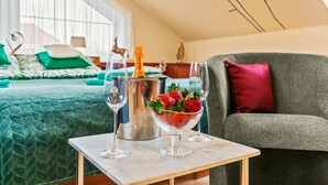 A hotel room with a bed, a grey sofa, a small table with a champagne bottle, glasses, and a bowl of strawberries. - Garden & Terrace Villa by Interhome (Karlin Liben)