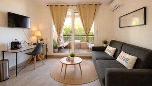 A modern living room with a sofa, a coffee table, a TV, and a balcony with curtains. - T2, swimming pool, Tennis MC (Beausoleil)