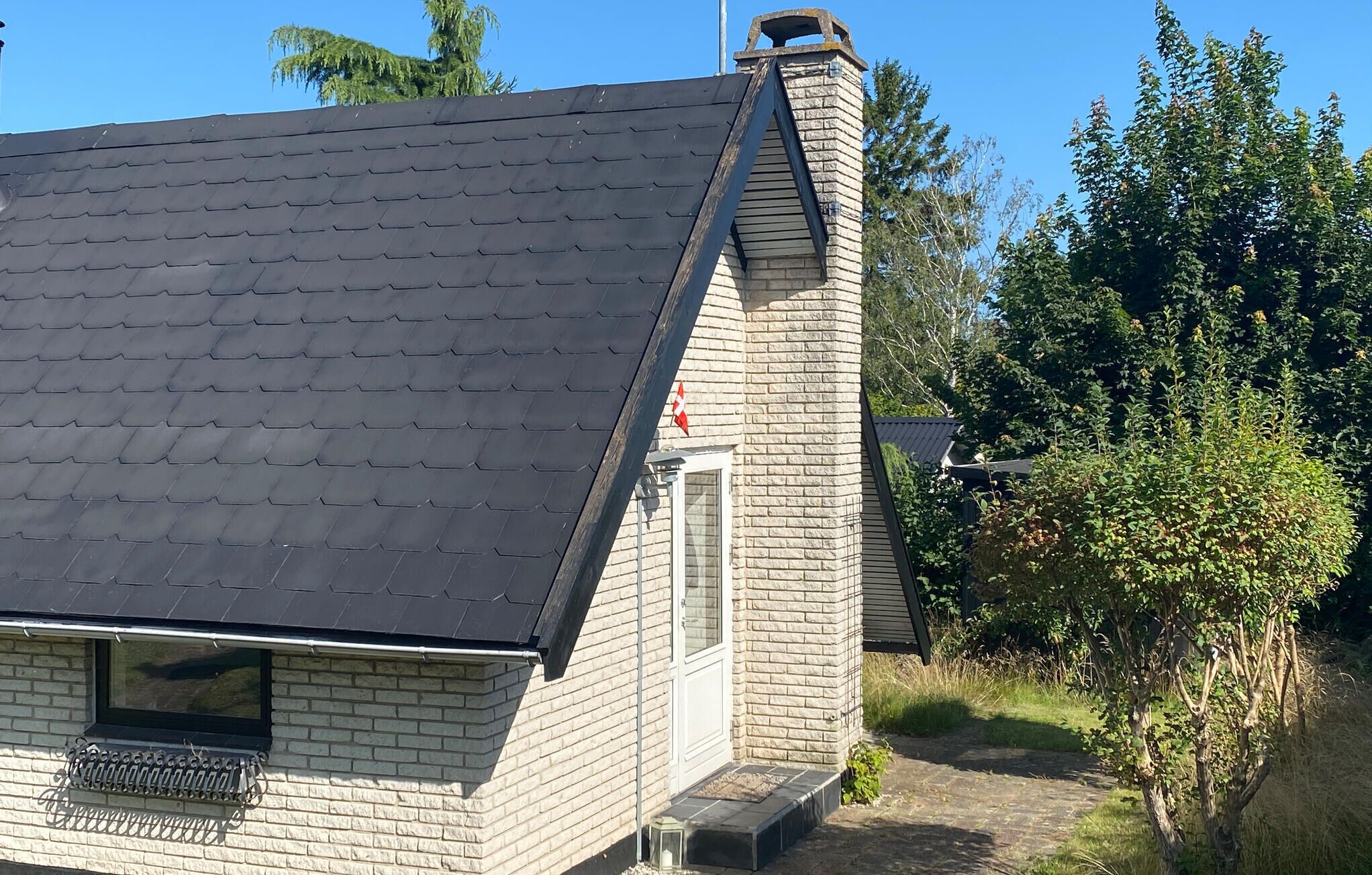 A house with a sloped roof and a brick chimney.