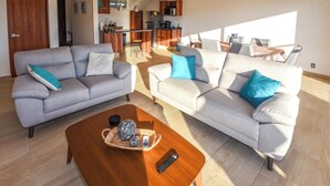 A modern living room with two sofas, a coffee table, and a kitchen in the background.