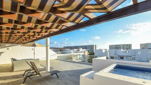 A rooftop terrace with a pool, lounge chairs, and a view of the cityscape.