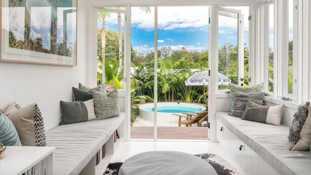 A bright, sunlit room with a large sliding glass door leading to a pool area. - Barefoot Bay Cottage (Byron Bay)