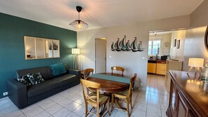 Una sala de estar con sofá, mesa de comedor, sillas y una cocina al fondo.