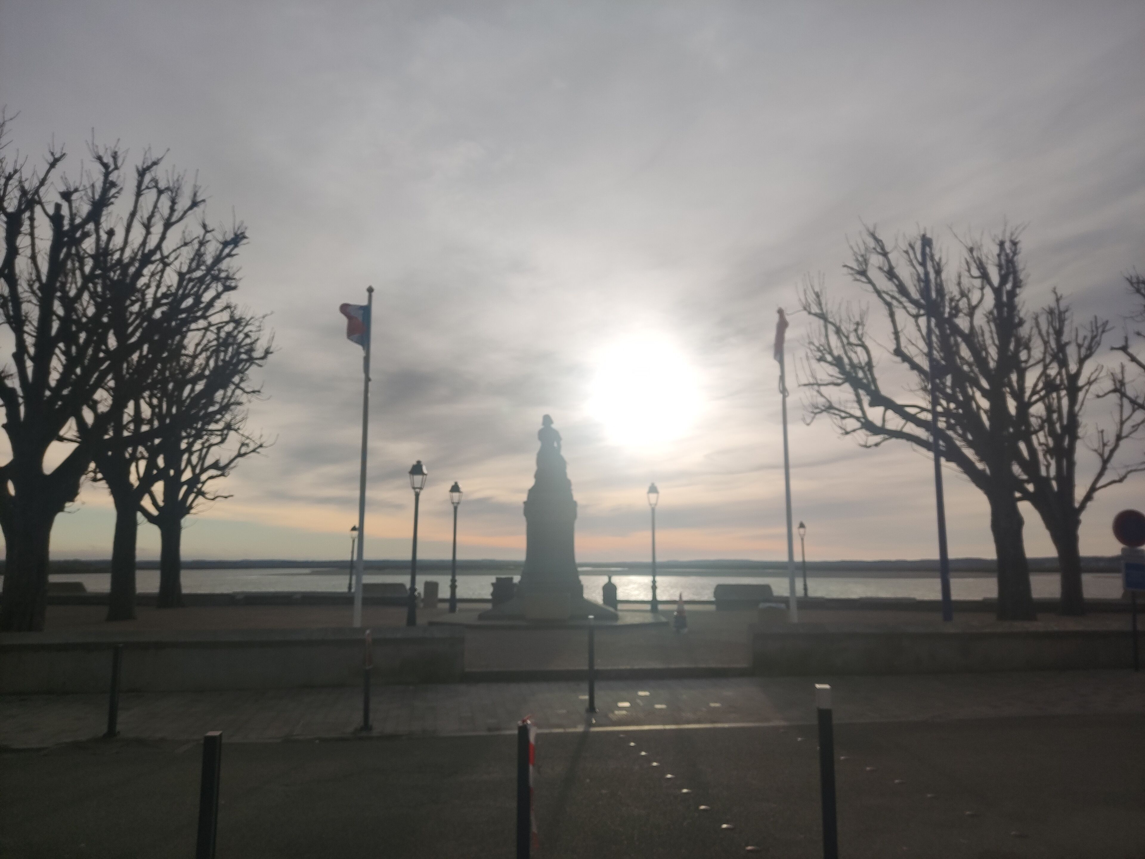 A statue in a park with bare trees and lampposts.