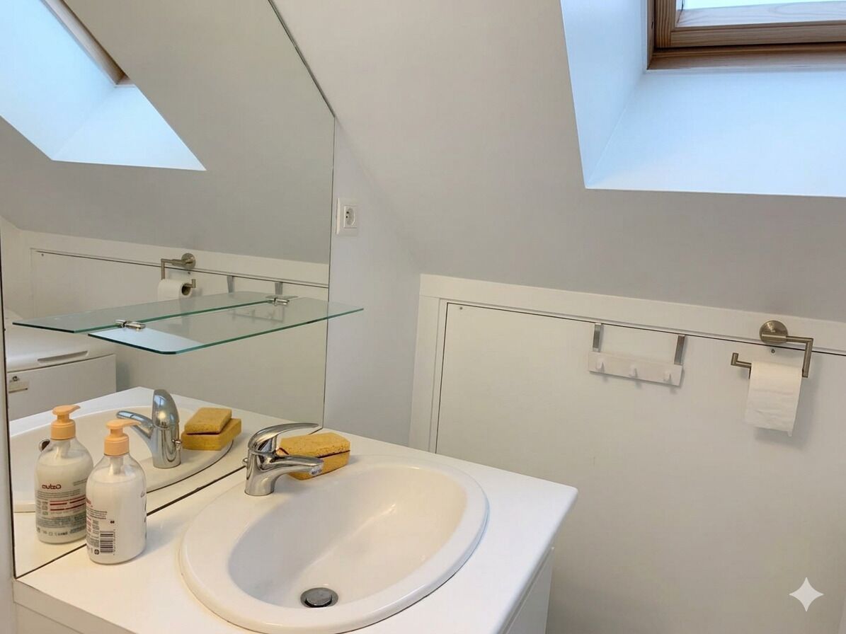 A modern bathroom with a skylight, a glass shelf, a sink, and toiletries.