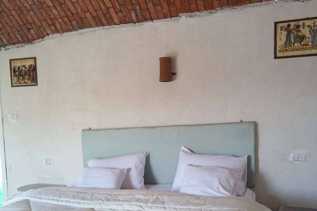 Een bed met hoofdeinde, wit beddengoed en een deken.