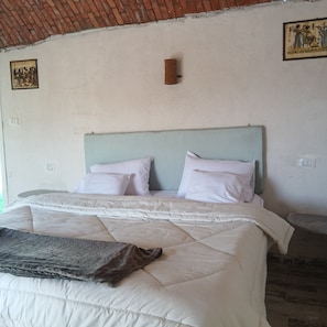 Un letto con una testiera, biancheria da letto bianca e una coperta.