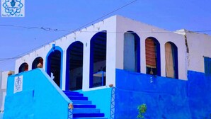 A building with a blue facade, arched windows, and a staircase leading to the entrance.