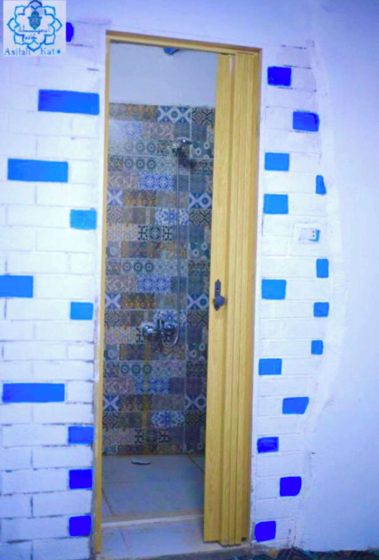 Una puerta que da a un baño con azulejos estampados.