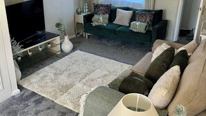 A living room with a TV, sofa, and lamp.