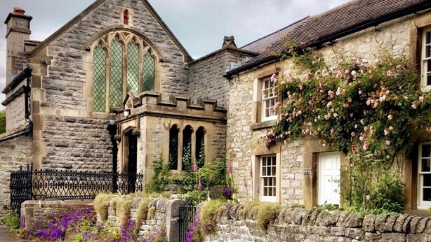 A stone building with a large arched window and a smaller window with a white door.