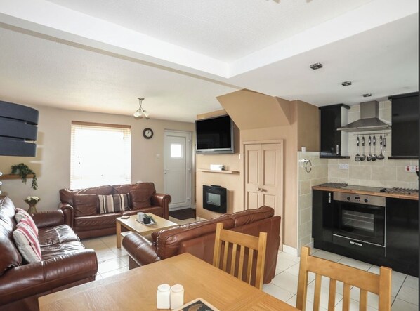 Cozy living space with a kitchenette, sofa, dining table, and TV.