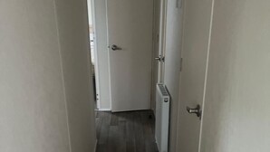 Um corredor estreito com um radiador à direita e uma porta no final.