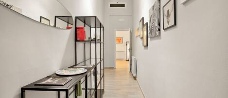 A hallway with a black metal console table, a mirror, and framed artwork on the walls.
