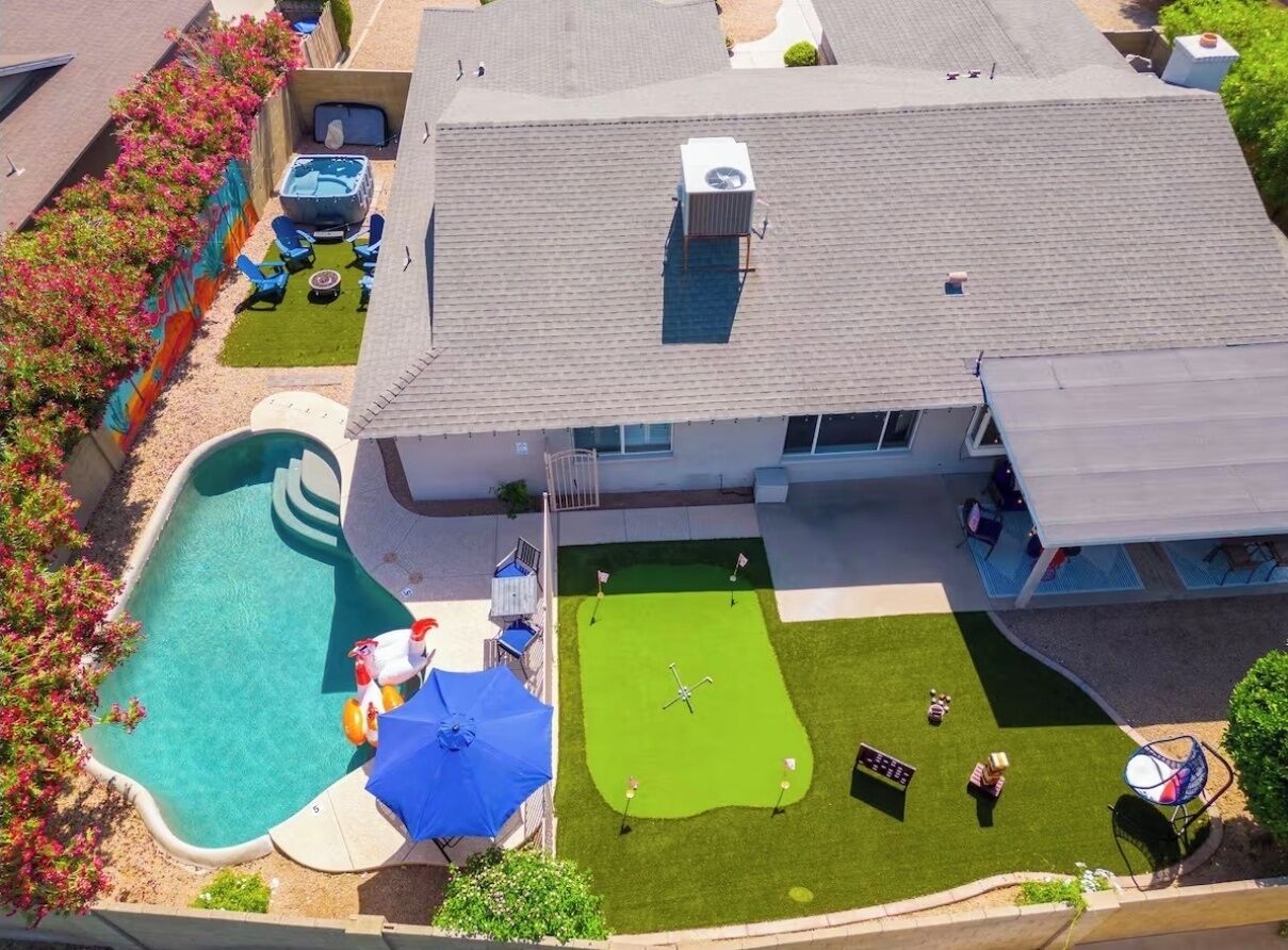 An aerial view of a house with a swimming pool, a hot tub, and a well-maintained lawn.