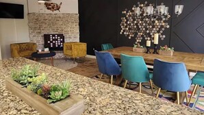 Un comedor moderno con chimenea de piedra, una mesa de madera y sillas azules.