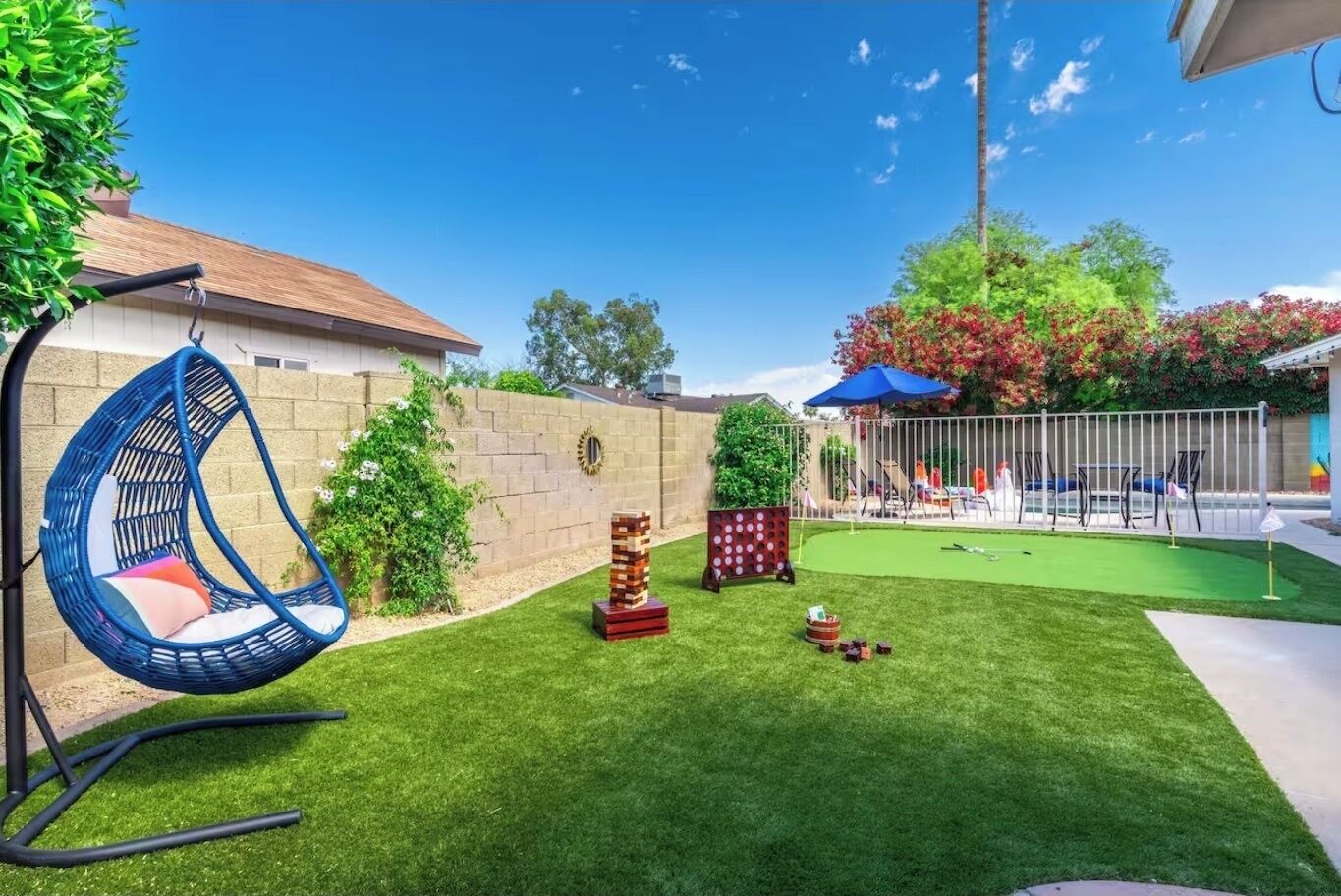 A backyard with a hanging chair, a small play area, and a lawn.