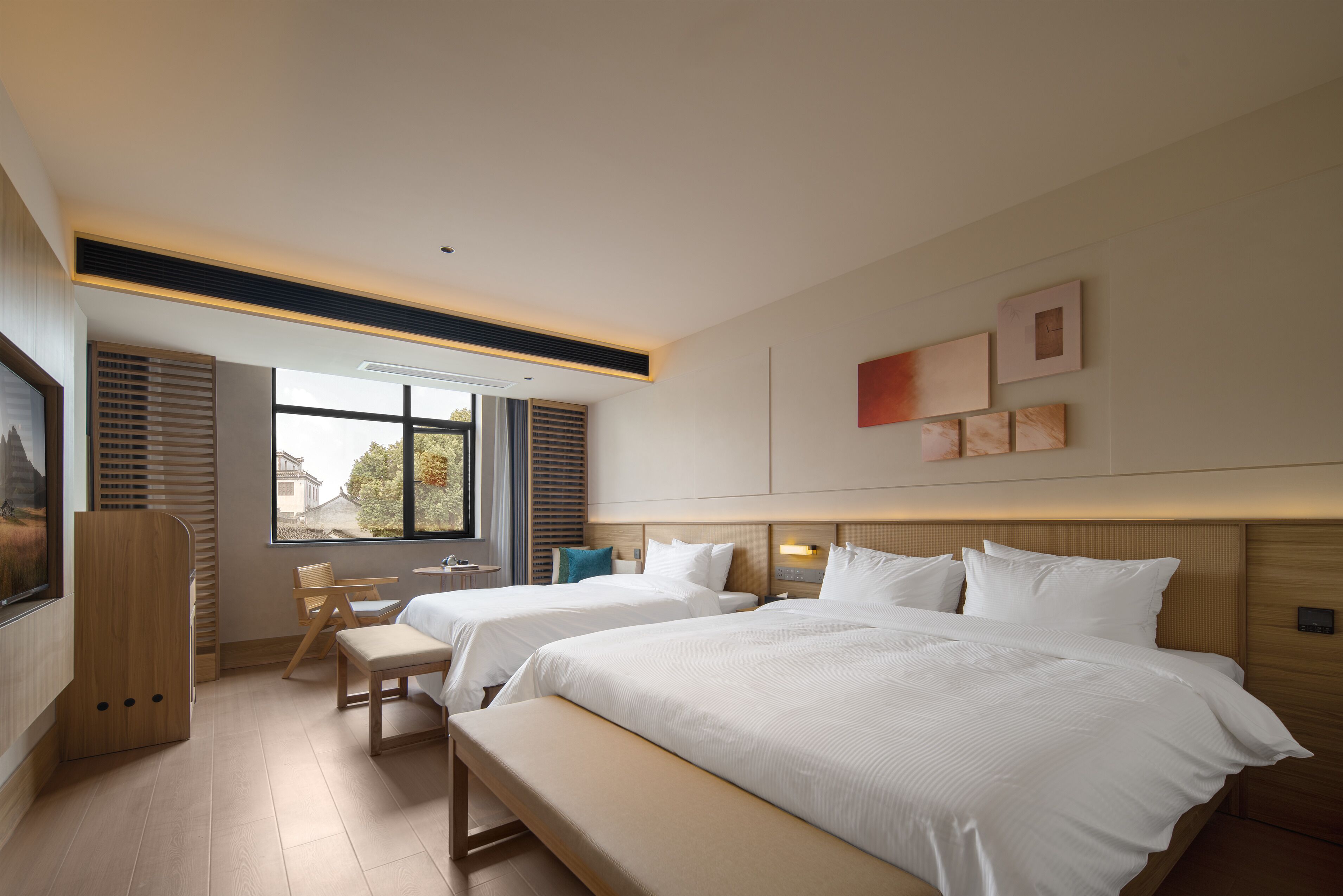 A modern hotel room with two beds, a bench, a desk, and a large window.