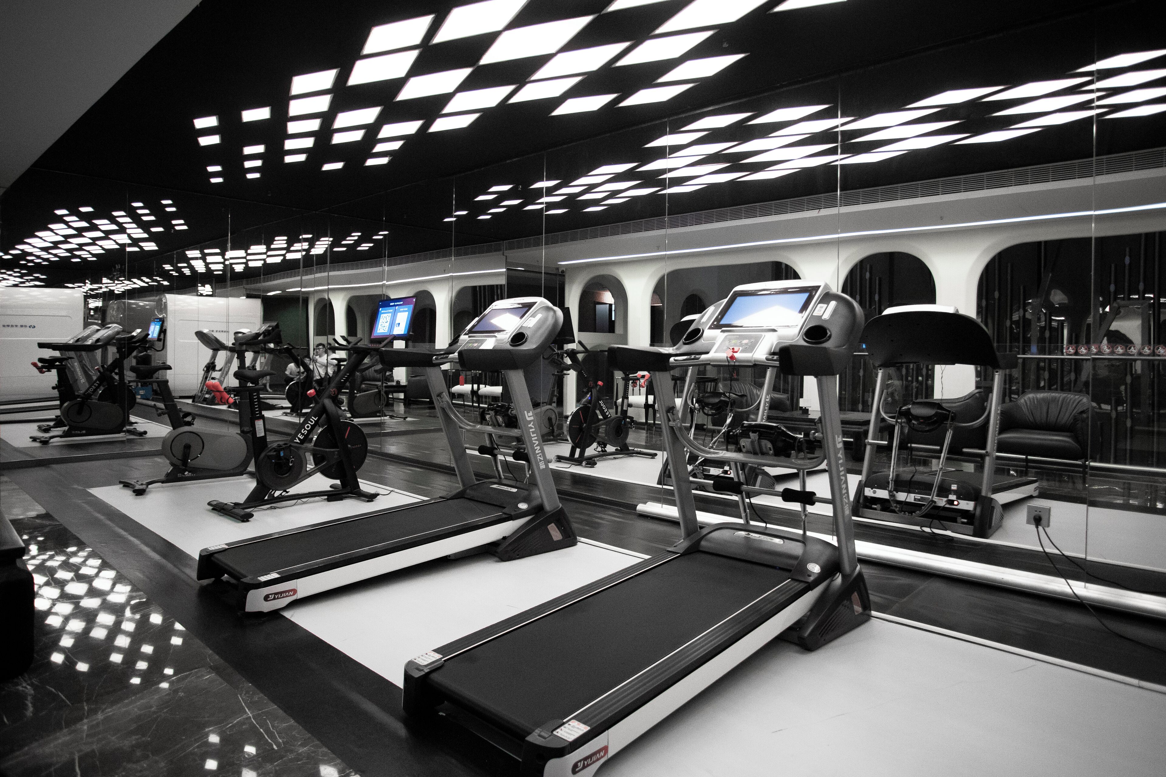 A modern gym with treadmills, stationary bikes, and elliptical machines.