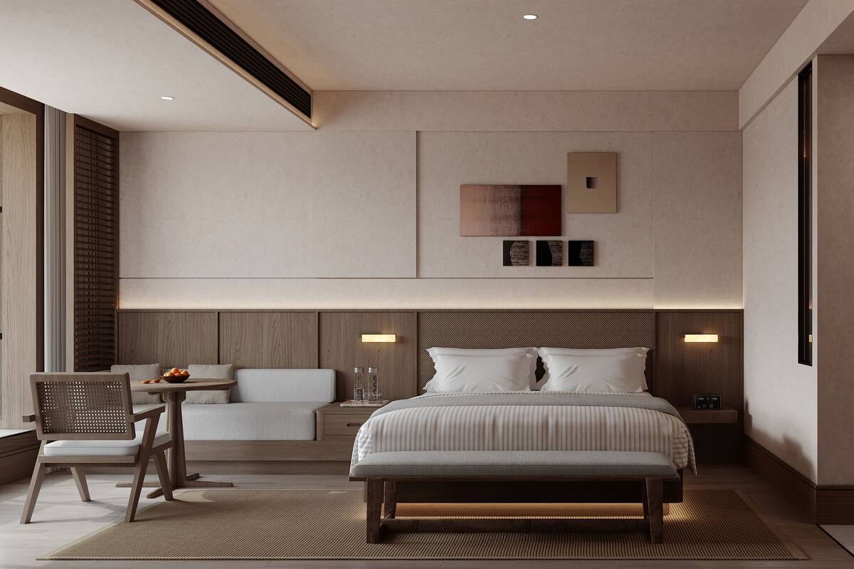 Habitación de hotel moderna con una cama grande, un escritorio con silla, una pequeña mesa con fruta, zona de ducha y vistas a la ciudad.