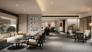 Un moderno vestíbulo de hotel con un sofá, sillas, una recepción y una pared decorativa.