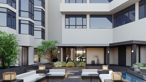 Un edificio moderno con un patio que cuenta con asientos al aire libre, una piscina y plantas en macetas.