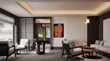 Un salon moderne comprenant un canapé, deux fauteuils, une table basse et une table à manger. Une grande fenêtre avec des stores, une plante en pot et une œuvre d’art abstraite ornent la pièce.