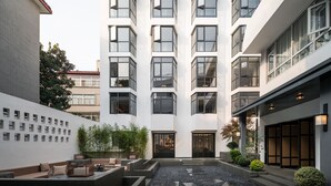 A modern building with multiple floors, large windows, and a courtyard with seating and plants. - Maiyue Hotel (Xi'an)