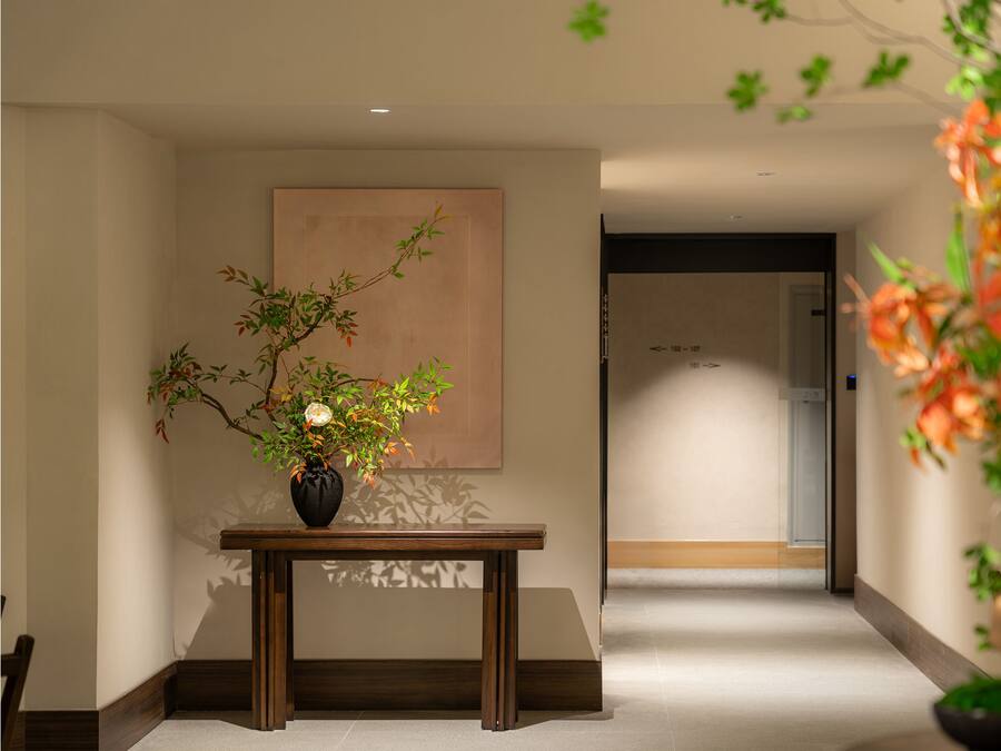 A hallway with a wooden table and a vase of flowers.