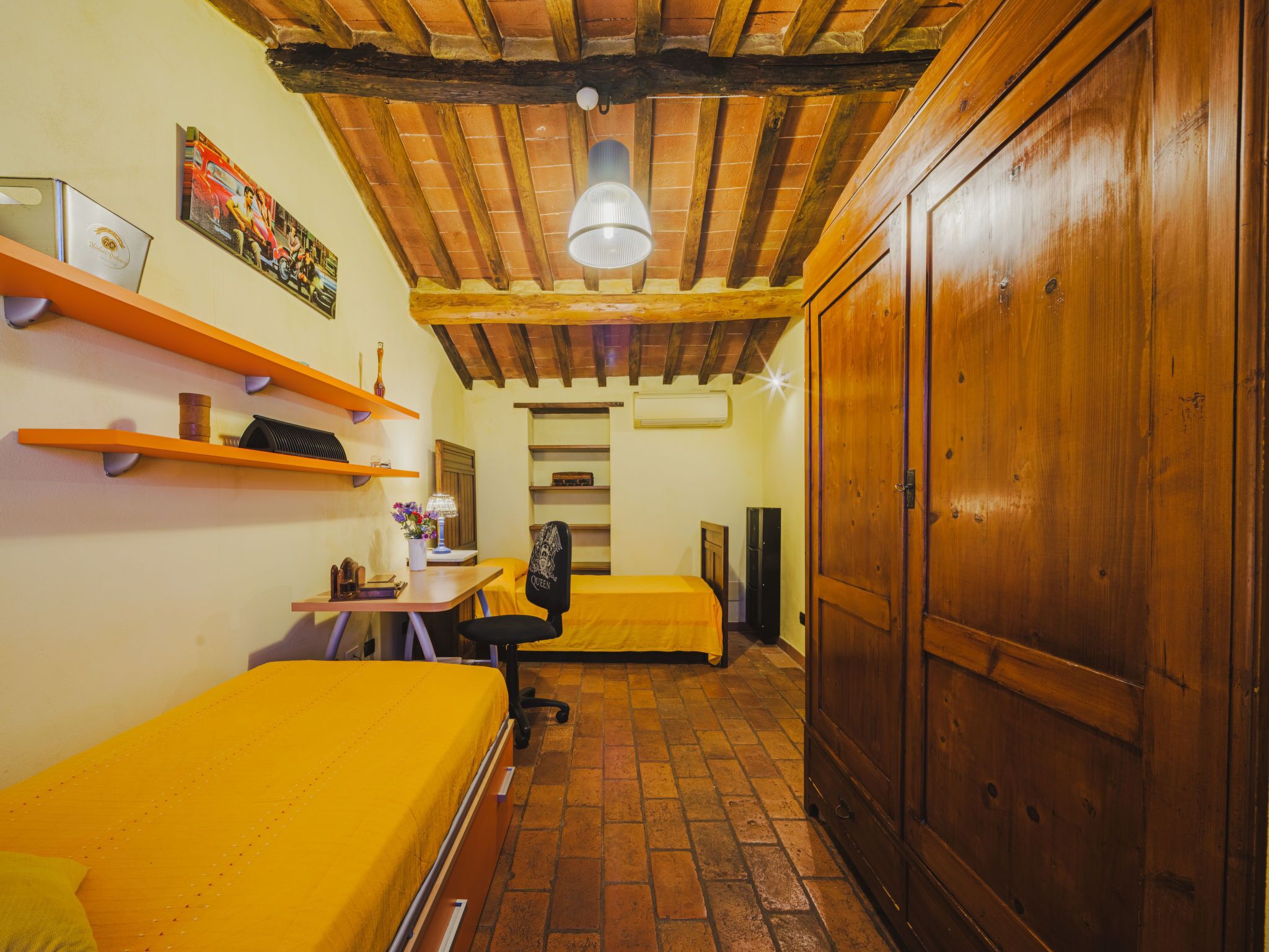 Una habitació amb dos llits, escriptori, cadira i armari.