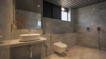A modern bathroom with a large mirror, a white sink, a toilet, and a shower area.