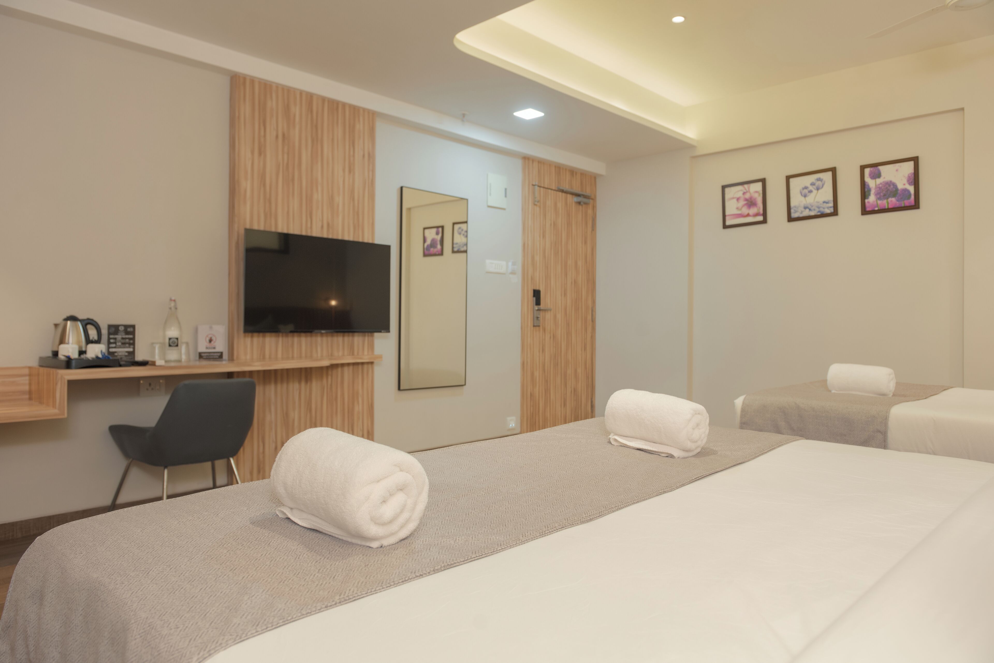 Una habitación de hotel con dos camas, televisión, escritorio con silla y espejo.
