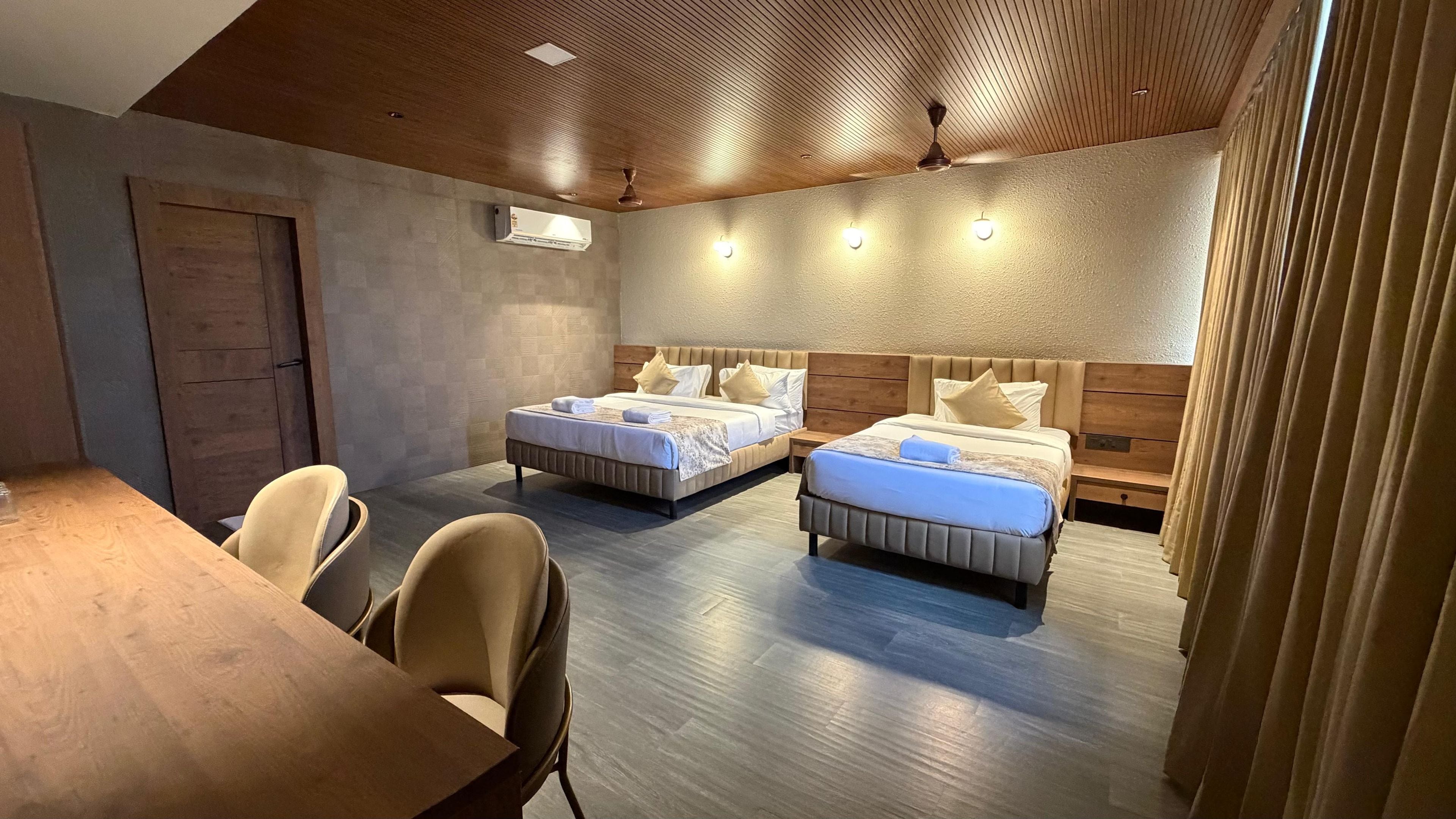 Quarto de hotel com duas camas, uma mesa de jantar e teto de madeira.