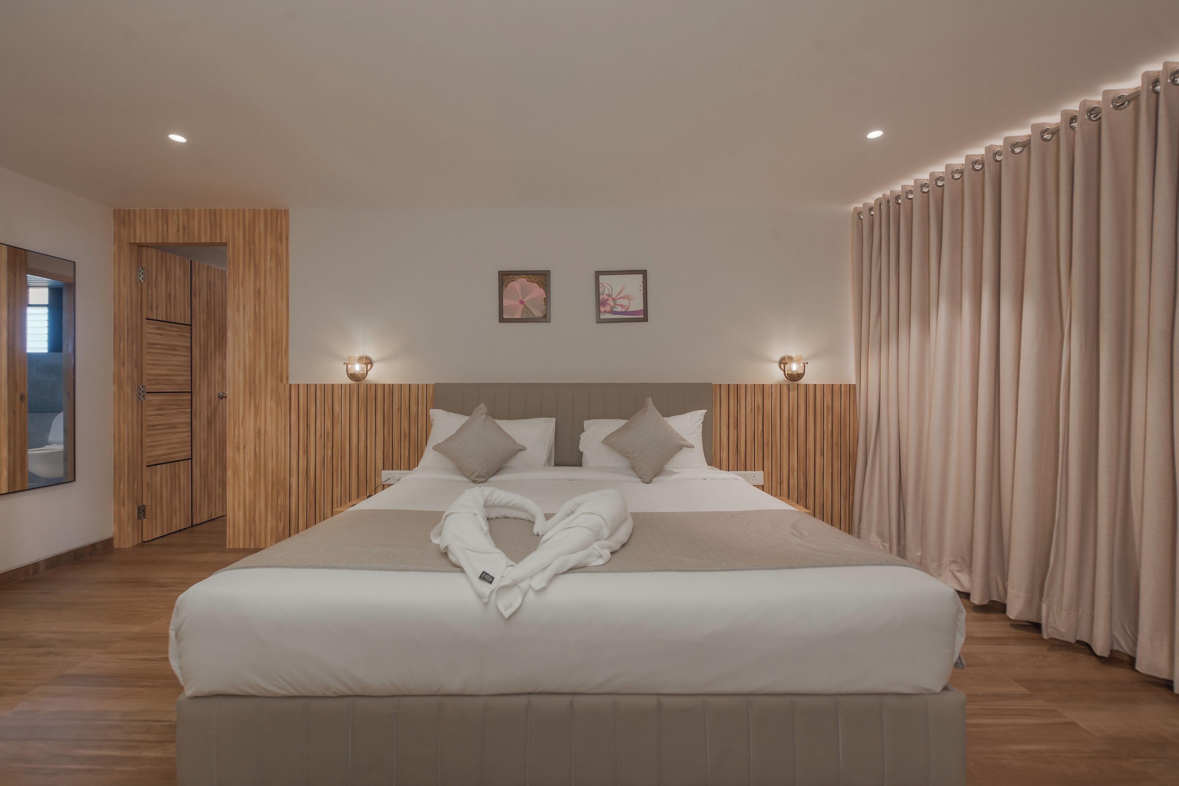 Una habitación de hotel moderna con una cama grande, paneles de madera en las paredes y vistas al exterior.