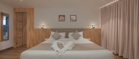 Una habitación de hotel moderna con una cama grande, paneles de madera en las paredes y vistas al exterior.