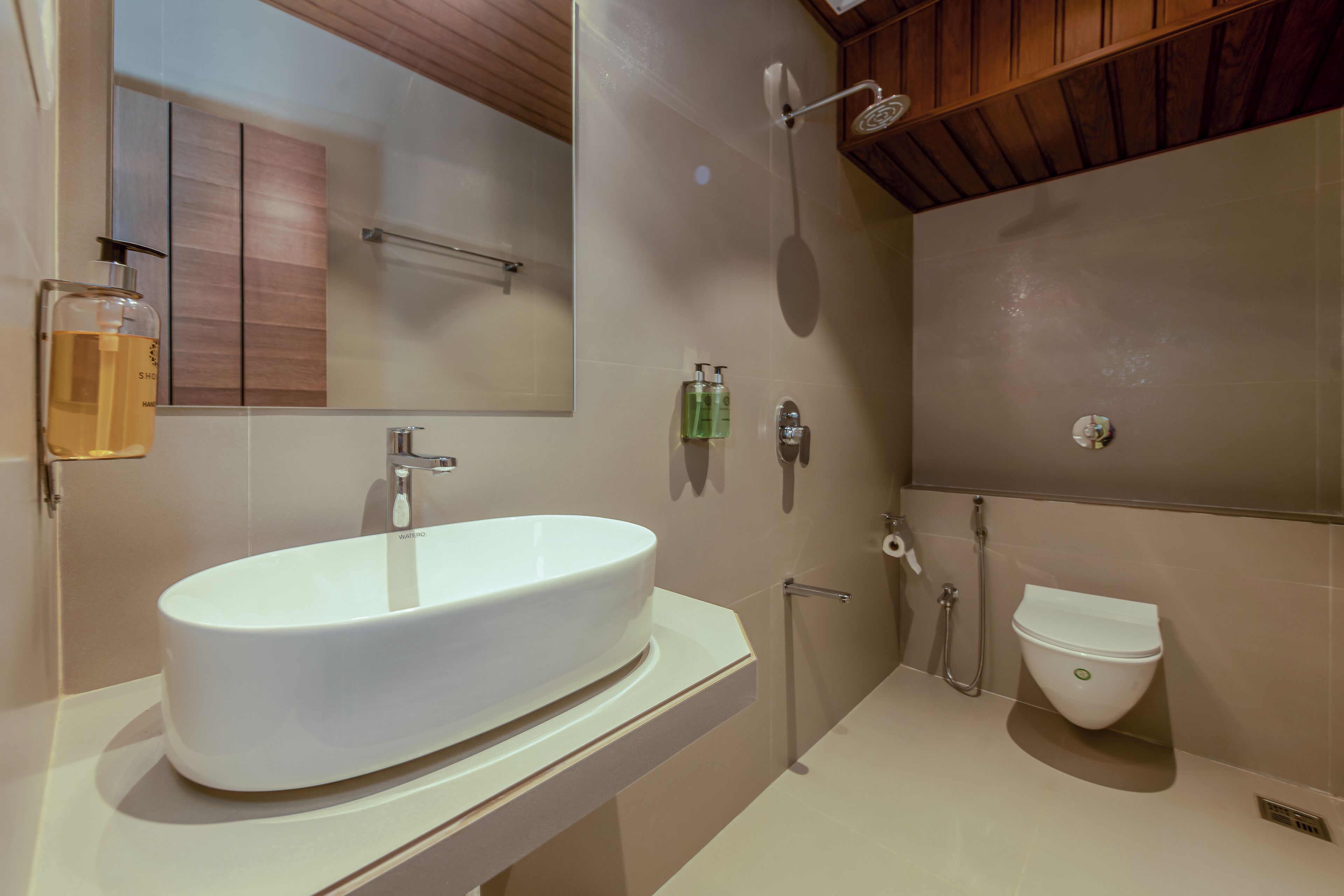 Un baño moderno con un lavamanos ovalado grande, un inodoro y una ducha.