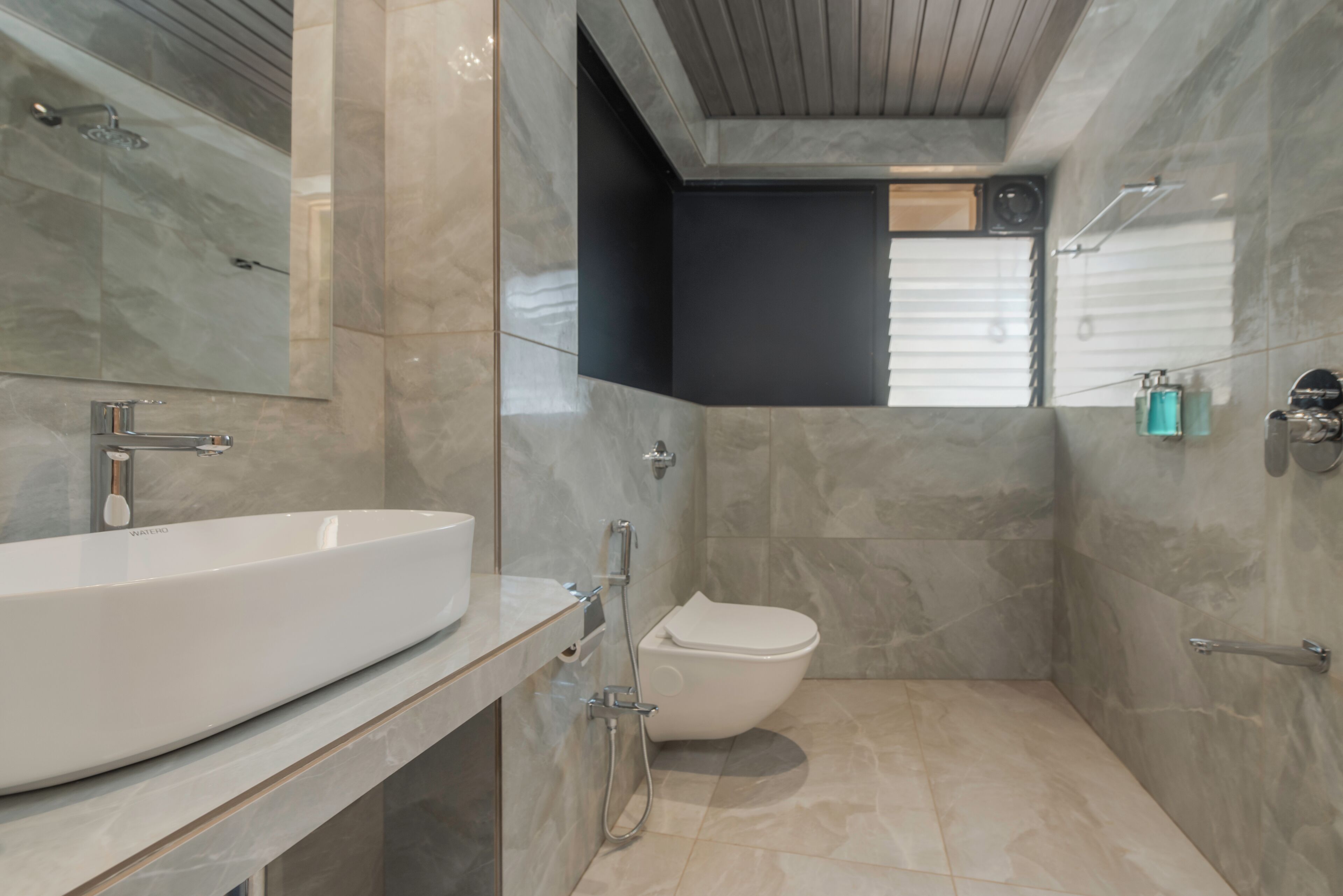 Un baño moderno con un lavamanos grande blanco, un inodoro y una ducha.