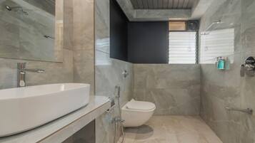 Un baño moderno con un lavamanos grande blanco, un inodoro y una ducha.