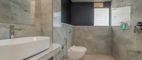 Un baño moderno con un lavamanos grande blanco, un inodoro y una ducha.